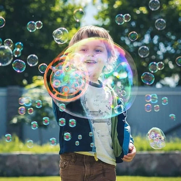 Child joyfully playing with large bubbles outdoors, showcasing fun with Dinosaur Bubble Machine for Kids.