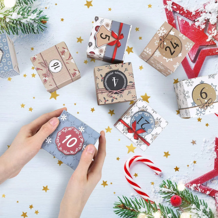 Hands holding a gift box from the Christmas Advent Calendar 2025 on a festive table with other decorated boxes.